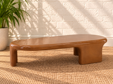 Load image into Gallery viewer, Klarisse caramel high-gloss concrete coffee table with elongated rounded top and sculptural waterfall-style supports.
