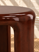 Load image into Gallery viewer, Image 5 of 5: Klarisse sculptural side table in chestnut high-gloss concrete with a rounded top and three curved integrated legs.

