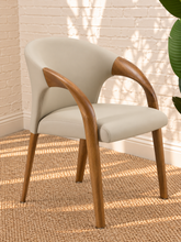 Load image into Gallery viewer, Kyra greige vegan leather dining armchair with curved back, sculpted solid ash wood arms and legs, and cushioned seat.
