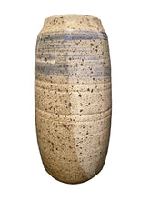 Load image into Gallery viewer, A handmade ceramic vase with a textured, speckled glaze in cream, beige, and brown, featuring a horizontal band of blue speckles near the top, set against a dark background.
