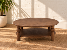 Load image into Gallery viewer, Leon two-tier coffee table in natural brown mango wood with a wide oval tabletop, lower shelf, and sculptural turned supports.
