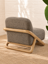 Load image into Gallery viewer, Lucia lounge chair with textured mocha upholstery, rounded seat and back, and sculptural curved natural wood sled frame
