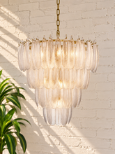 Load image into Gallery viewer, Maine chandelier with cascading tiers of elongated textured clear glass pieces suspended from an iron frame and chain.
