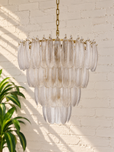 Load image into Gallery viewer, Maine chandelier with cascading tiers of elongated textured clear glass pieces suspended from an iron frame and chain.
