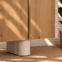 Load image into Gallery viewer, Marlee four-door credenza with natural oak veneer doors, faux travertine surround, interior shelving, and two rounded pedestal legs.
