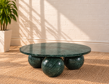 Load image into Gallery viewer, Martha round Forest Night marble coffee table with three spherical ball-shaped bases and natural dark green stone veining.
