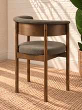 Load image into Gallery viewer, Mila mocha upholstered dining chair with curved open back, round cushioned seat, warm wood frame, and cylindrical legs
