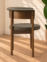 Load image into Gallery viewer, Mila mocha upholstered dining chair with curved open back, round cushioned seat, warm wood frame, and cylindrical legs
