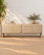 Load image into Gallery viewer, Miles natural light wood credenza in mindi and bayor wood with four rounded cabinet fronts, subtle wood grain, and waterfall-style sides.

