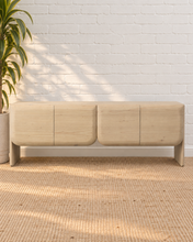 Load image into Gallery viewer, Miles natural light wood credenza in mindi and bayor wood with four rounded cabinet fronts, subtle wood grain, and waterfall-style sides.

