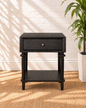 Load image into Gallery viewer, Mina natural black one-drawer nightstand with round metal knob, spindle-detailed wood legs and an open lower storage shelf.

