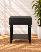 Load image into Gallery viewer, Mina natural black one-drawer nightstand with round metal knob, spindle-detailed wood legs and an open lower storage shelf.
