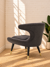 Load image into Gallery viewer, Image 4 of 4: Mirella upholstered lounge chair in Smoky Charcoal with sculptural back, plush seat, and brass-capped legs
