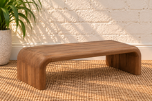 Load image into Gallery viewer, Molly natural brown mindi wood coffee table with rounded rectangular top and wide waterfall-style legs.
