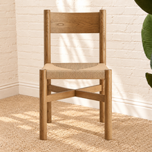 Load image into Gallery viewer, Amelie natural solid oak dining armchair with woven paper-rope seat, curved wood backrest, slim armrests, and X-shaped stretcher
