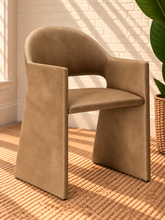 Load image into Gallery viewer, Nora tan vegan leather dining armchair with curved barrel back, open-back detail, padded seat, and wide upholstered sides

