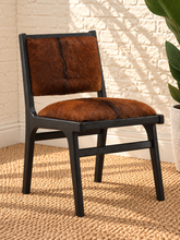 Load image into Gallery viewer, Odessa dining chair in natural chestnut genuine goat hide with a tall upholstered back, rounded seat, and exposed teak wood frame.
