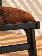 Load image into Gallery viewer, Odessa dining chair in natural chestnut genuine goat hide with a tall upholstered back, rounded seat, and exposed teak wood frame.
