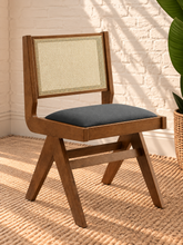 Load image into Gallery viewer, Remi dining chair with warm wood frame, natural rattan cane backrest, black faux leather seat, and angled A-frame legs
