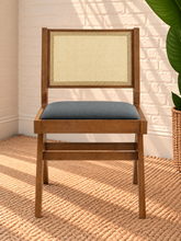 Load image into Gallery viewer, Remi dining chair with warm wood frame, natural rattan cane backrest, black faux leather seat, and angled A-frame legs

