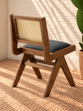 Load image into Gallery viewer, Remi dining chair with warm wood frame, natural rattan cane backrest, black faux leather seat, and angled A-frame legs

