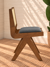 Load image into Gallery viewer, Remi dining chair with warm wood frame, natural rattan cane backrest, black faux leather seat, and angled A-frame legs
