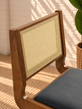 Load image into Gallery viewer, Remi dining chair with warm wood frame, natural rattan cane backrest, black faux leather seat, and angled A-frame legs
