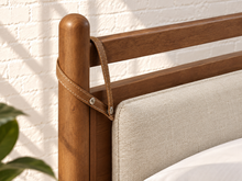 Load image into Gallery viewer, Rocco Queen platform bed with Walnut rubberwood frame, Greige heathered fabric headboard pillow, and faux leather straps.
