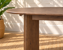 Load image into Gallery viewer, Rohan 79-inch oval dining table in dark walnut solid Mindi wood with rounded tabletop edges and architectural panel legs.

