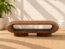 Load image into Gallery viewer, Rolly acacia wood coffee table in natural brown with rounded edges, open shelf, and two cylindrical pedestal feet.
