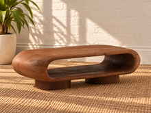 Load image into Gallery viewer, Rolly acacia wood coffee table in natural brown with rounded edges, open shelf, and two cylindrical pedestal feet.
