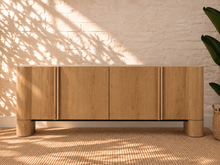 Load image into Gallery viewer, Sadie natural oak four-door credenza with rounded edges, integrated legs, white oak veneer, and interior shelving.
