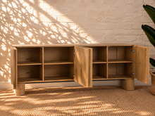 Load image into Gallery viewer, Sadie natural oak four-door credenza with rounded edges, integrated legs, white oak veneer, and interior shelving.
