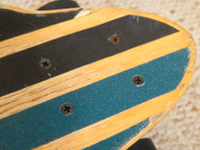 Load image into Gallery viewer, Close-up of a skateboard deck showing alternating stripes of natural wood, black grip tape, and teal grip tape, with visible screws and wear on the surface.
