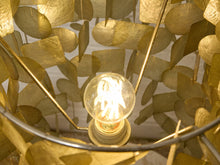 Load image into Gallery viewer, Close-up of a decorative pendant light with a glowing clear bulb inside a cage made of overlapping metallic gold leaf-like discs and thin gold metal rods.
