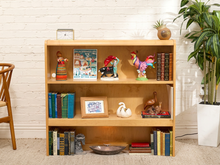 Load image into Gallery viewer, Vintage blonde wood low bookcase with two open shelves, rounded top edge, and simple rectangular silhouette.

Era:  Late 20th Century

Style:  Mid-Century Modern · Scandinavian Inspired · Minimalist
