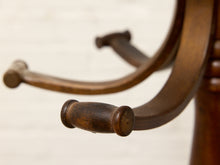 Load image into Gallery viewer, Close-up detail of a dark brown wooden chair's curved armrest and turned cylindrical end caps against a light off-white background.
