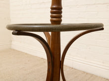 Load image into Gallery viewer, A close-up of a vintage wooden stand or table base with curved legs and a round gray stone top, set against a white brick wall and beige carpet.
