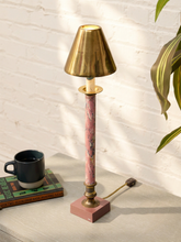 Load image into Gallery viewer, A table lamp with a pink marble column, a brass shade and base, and a matching pink marble base, styled on a tabletop next to a mug and books against a white brick wall.
