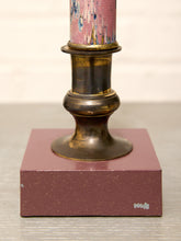 Load image into Gallery viewer, Close-up of a table lamp base featuring a square dusty rose marble or stone pedestal, a dark bronze metal candle holder, and a pink marbled candle partially visible at the top.
