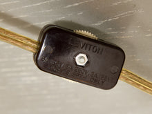 Load image into Gallery viewer, A close-up of a Leviton electrical connector block with gold-colored wires passing through it, set against a light gray textured background.
