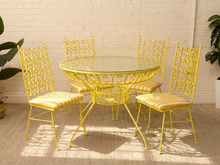 Load image into Gallery viewer, Vintage Arthur Umanoff yellow wrought iron patio dining set with round glass-top table and four chairs with yellow and white striped cushions.
