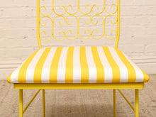 Load image into Gallery viewer, A yellow metal chair with a striped yellow and white cushioned seat, shown against a white brick wall background.
