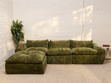 Load image into Gallery viewer, 70’s-style olive green modular sofa with deep loose cushions, rounded arms, textured upholstery, and matching square ottoman.
