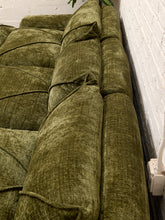 Load image into Gallery viewer, An olive green textured fabric sofa cushion or chair component shown in a close-up angled view against a white brick wall.
