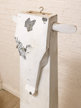 Load image into Gallery viewer, A rustic white-painted wooden post with a metal hanging hook at the top and a small white cylindrical protrusion on the side, shown against a white brick wall.
