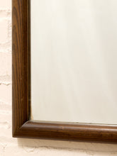 Load image into Gallery viewer, Close-up of a dark brown wooden frame with a beveled corner, mounted on a textured off-white brick wall.
