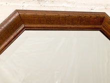 Load image into Gallery viewer, Close-up of a hexagonal mirror with a thick, dark brown wood frame, showing a light off-white surface reflecting the background.
