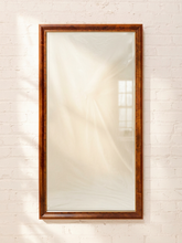 Load image into Gallery viewer, A tall rectangular wall mirror with a thick, polished dark brown wooden frame, mounted on a white painted brick wall.
