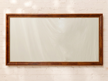 Load image into Gallery viewer, A rectangular wall mirror with a thick, polished dark brown wooden frame, mounted on a white painted brick wall.
